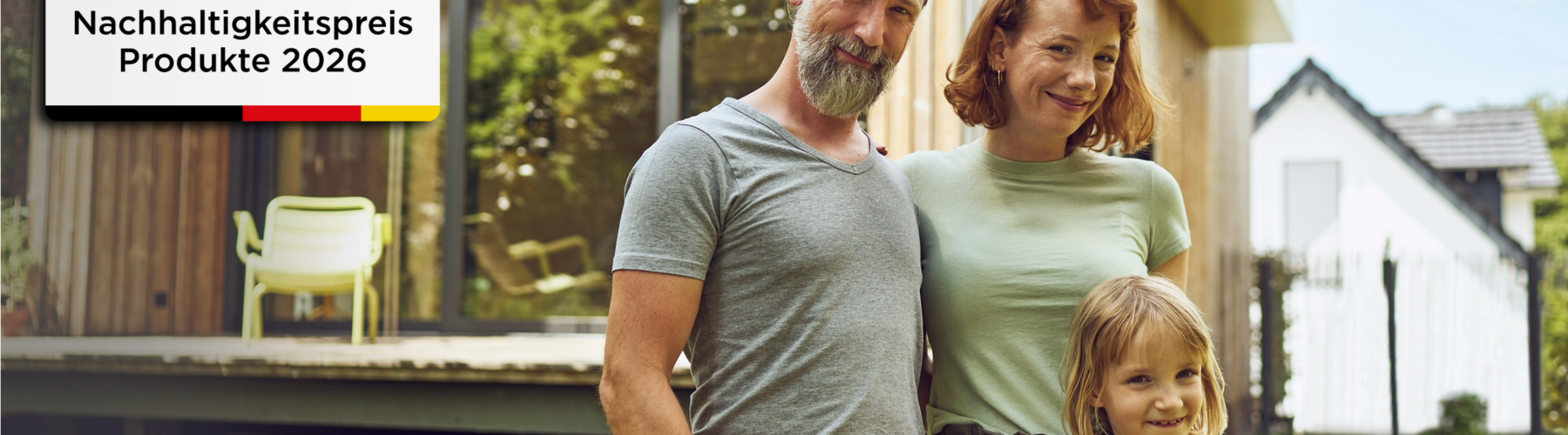 Junge Familie vor ihrem neu gebauten Haus und Siegel "Nachhaltigkeitspreis Produkte 2026"